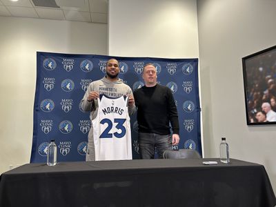 Monte Morris holding Timberwolves jersey with Tim Conelly.